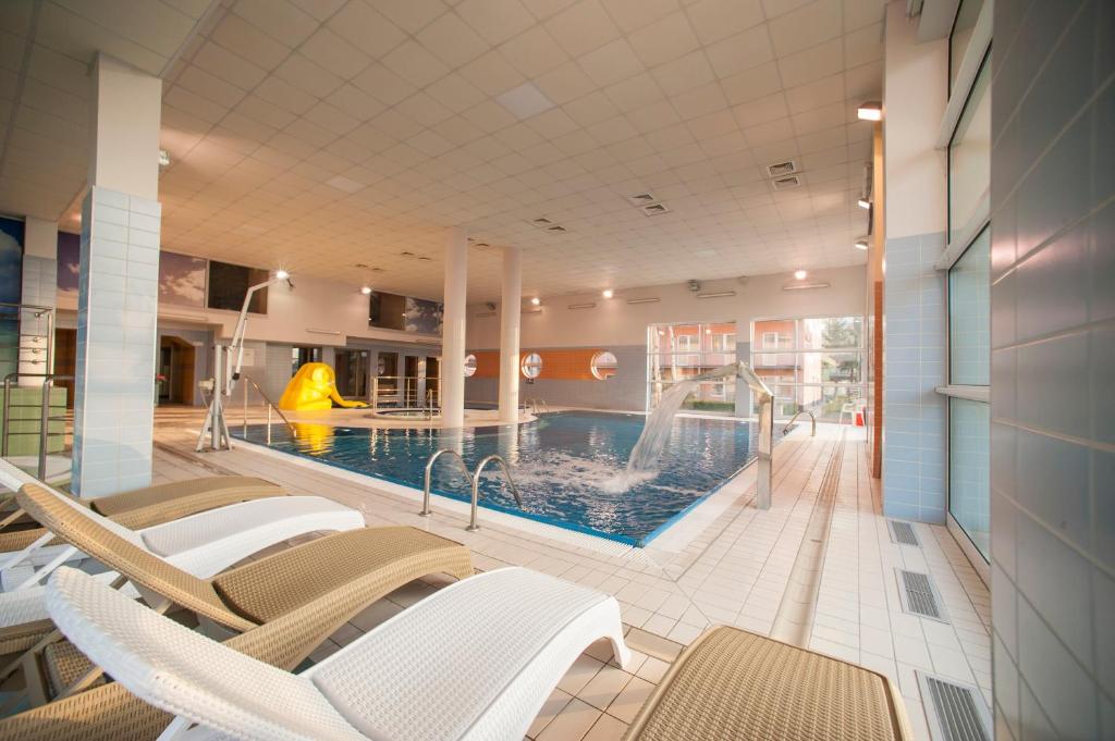Hallenbad mit Wasserrutsche und Liegen im Akces Medical FIT & SPA in Dźwirzyno